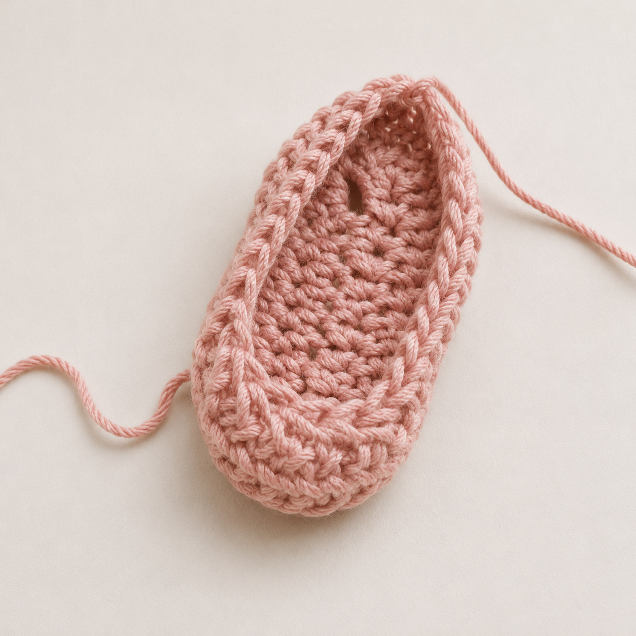 Completed Row 4 of crochet baby shoe body showing toe decreases
